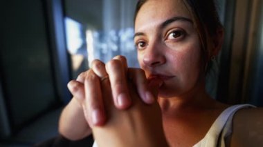 Contemplative woman thinking deeply at apartment balcony. Pensive female person in her 30s with thoughtful emotion. closeup face serious expression