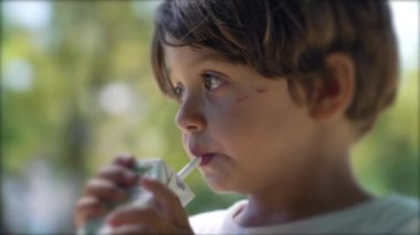 Çocuk karton kutudan meyve suyu içer. Küçük bir çocuk meyve suyu içerken düşüncelere daldı.