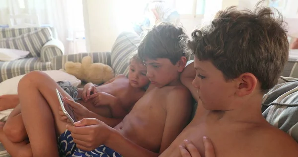 아이들은 소파에 앉아서 태블릿 가젯에서 영화를 있습니다 — 스톡 사진
