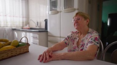 80 'li yaşlarındaki bunalımlı düşünceli yaşlı kadın mutfakta yalnızlığını ve yalnızlığını ifade ediyor. Yaşlı bir insanın yalnız üzüntüsü.