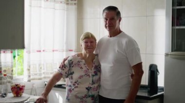 Orta yaşlı yetişkin bir çocuk, 80 'li yaşlarda yaşlı annesiyle birlikte mutfakta poz veriyor. Gerçek hayattaki nesiller arası insanların özgün yaşam tarzı