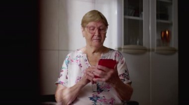Evde Cep Telefonu Kullanan Teknoloji Tasarruf Yaşlısı Kadın, Modern Teknoloji ve Çevrimiçi Tarayıcı ile Meşgul