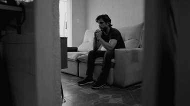 Evdeki koltukta yalnız genç bir adam kendini yalnız hissediyor. 30 'lu yaşlarda tek renkli dramatik siyah beyaz depresyon geçiren endişeli bir erkek.