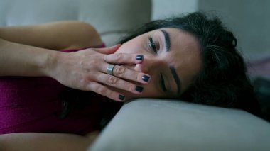 Depresyondaki kadın kanepede yatıyor. 30 'lu yaşlarda, duygusal sıkıntıdan muzdarip mutsuz yüzlü bir kadın.