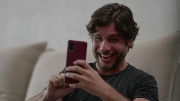 Счастливый Мужчина Позитивно Реагирует Уведомления Новостях Мобильном Телефоне Сидя Дома — стоковое фото