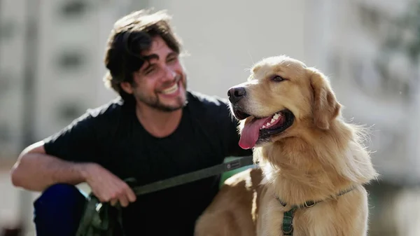 晴れた日に公園でゴールデン レトリバー ドッグとカメラのポーズをとる若い男がいる 犬仲間と週末のアクティビティを楽しむ人 — ストック写真