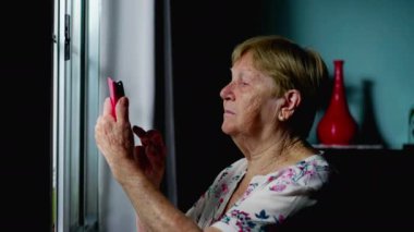 Ev Penceresinin Yanında Telefon Kullanan Yaşlı Kadın, Yaşlılıkta Modern Teknolojinin Kullanımını Açıklıyor