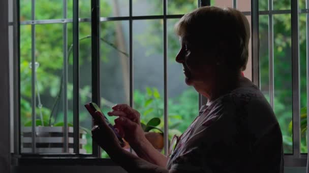 Evde Modern Teknolojiyi Kullanan Yaşlı Bir Kadının Silueti Telefon Tutan — Stok video