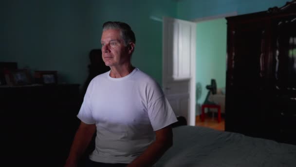 一个忧心忡忡的中年男人坐在床边 脸上带着沉思的表情 老年男性在家里 随意的家庭生活场景 — 图库视频影像