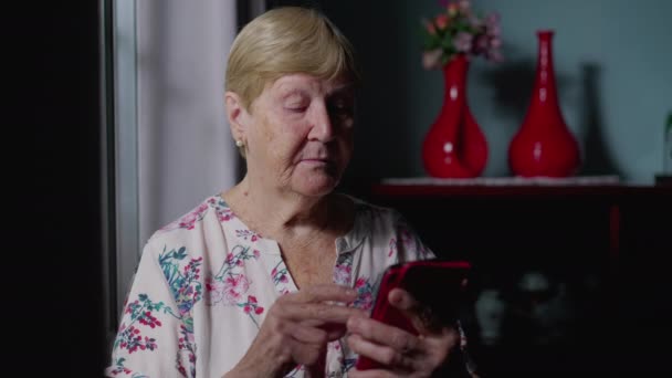 老年妇女通过电话逐窗打转互联网 说明现代技术在家庭中的应用 — 图库视频影像