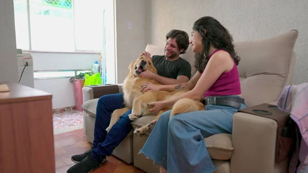 Joyful people playing with their pet Dog on couch at home apartment