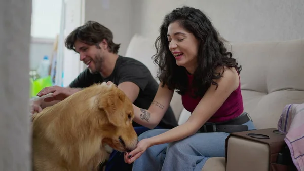 一对快乐的夫妇坐在沙发上和他们的金毛猎犬交流 — 图库照片