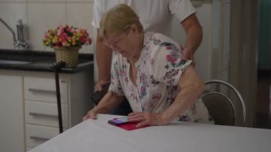 Yaşlı bir kadın, gerçek hayat tarzında, yaşlılığı resmeden gerçek bir yaşam tarzıyla evdeki sandalyesinden kalkıyor.