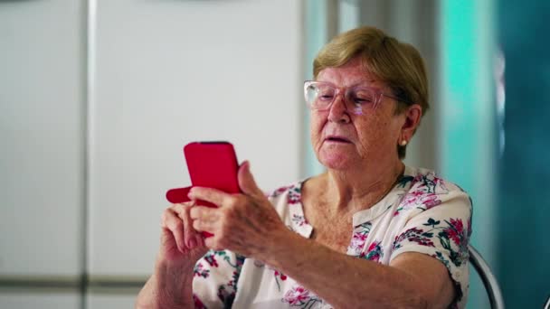 老妇人在家里使用智能手机 老年家庭生活方式 掌握现代技术 凝视着手机屏幕 — 图库视频影像
