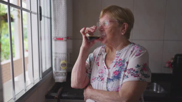 Μια Ηλικιωμένη Γυναίκα Πίνει Καφέ Στην Κουζίνα Του Παραθύρου Ένας — Αρχείο Βίντεο