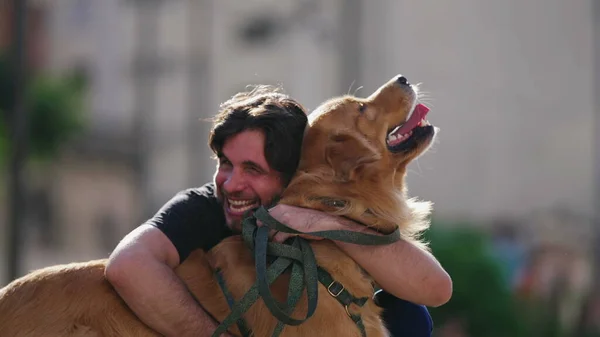 Happy dog owner laughing and smiling while hugging his Golden Retriever dog outside at park
