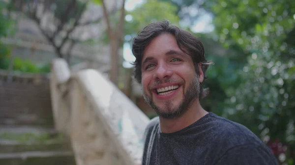 stock image Handsome Young Man Smiling at City Park standing outside in beautiful sunny day. 30s male person portrait face close up looking at camera