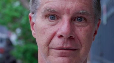 Orta yaşlı bir adam şok olmuş bir ifadeyle kameraya bakıyor.