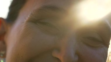 40 'lı yaşlarda bir kadın açık havada mercekle gözlerini kapatıyor. Rüya gibi güneş ışığıyla kadın gözlerine yakın çekim