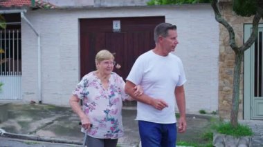 Orta yaşlı bir oğul yaşlı bir anneye yürümesi için yardım ediyor. Bir erkek son sınıf öğrencisini önemser ve destekler. Yaşlılık ev hayatı rutini