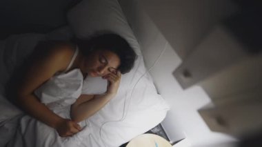 Pensive Woman laid in bed at night turns off lamp side. Thoughtful female person lying down going to sleep