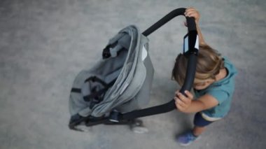 Bebek arabasını dışarı iten sevimli çocuk manzarası. Küçük çocuk hafta sonu parkta aile aktiviteleri sırasında araba sürüyor.
