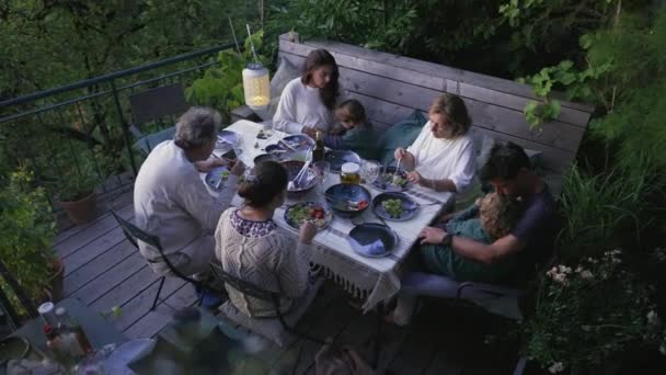 家族で一緒に家のパティオの裏庭で食べ物を食べる 屋外庭園には祖父母や子供たちが集まりました — ストック動画