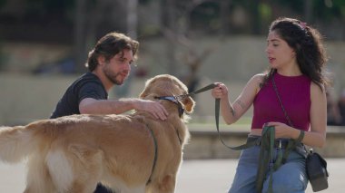 Şehir parkında köpekleri tasmalı bir çift. Erkek ve kadın, Golden Retriever Pet ile günlük yaşam tarzı rutini