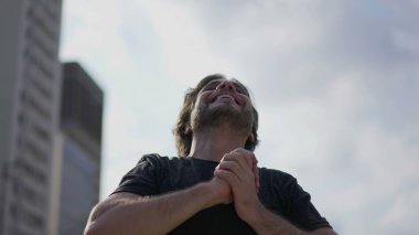 Açık havada duran dikkatli genç adam başarıyı kutluyor. Dalgın erkek doğanın ve farkındalığın tadını çıkarıyor.