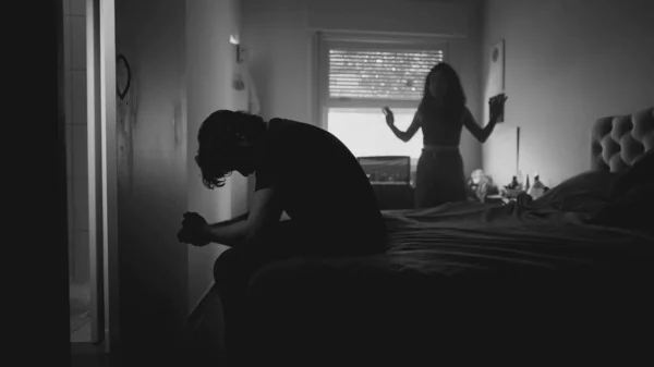 関係の崩壊 夫婦喧嘩と言い争い 女性のパートナーが寝室で彼を叫ぶ間 欲求不満で顔を覆う落ち込んでいる男 モノクロームのドラマティックな黒と白 — ストック写真
