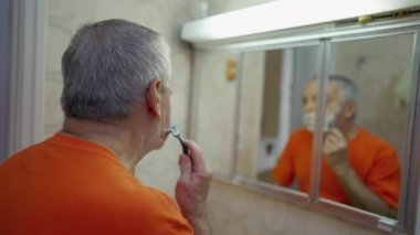 Son sınıf öğrencisi banyo aynasının önünde sakalını tıraş ediyor. Yaşlılık ev hayatı tarzı sabah ritüeli.