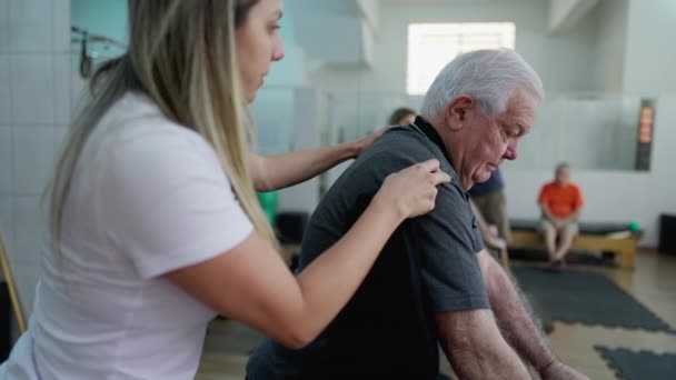 女普拉提指导员指导老年男子在理疗室内使用机器进行锻炼 — 图库视频影像