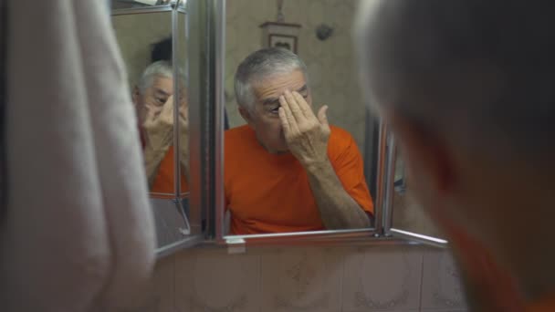 朝の儀式で鏡の前で身づくろいする先輩 70代の高齢者の家庭生活は 顔や皮膚を検査準備を取得 — ストック動画