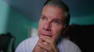 Düşünceli orta yaşlı bir adam evdeki sorunları düşünüp taşınıyor. Derin düşüncelere dalmış bir yüz ifadesi takınıyor.