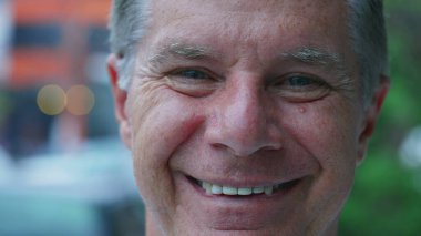 Şehir sokağında dikilirken kameraya gülümseyen orta yaşlı mutlu bir adam. Yaşlı insanın makro görüntüsü