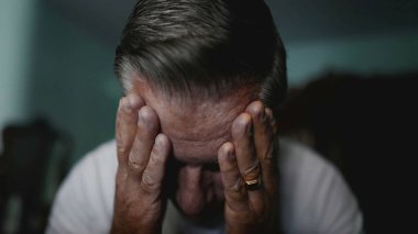 Beyaz, orta yaşlı bir adam, hayatın zorluklarıyla mücadele ediyor, baş ağrısı ve endişeden muzdarip, umutsuzluk içinde saklanan biri.