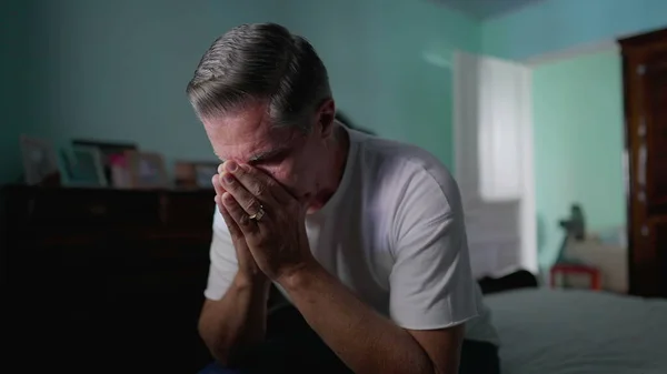 stock image Stressed Middle-Aged Man Feeling Anxiety, Sitting by Bedside Depicting Mental Struggle and Preoccupation, suffering in quiet despair alone