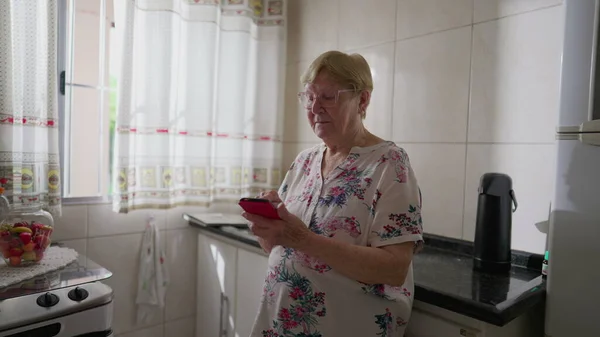 Mujer Anciana Usando Dispositivo Teléfono Celular Mientras Apoya Fregadero Cocina — Foto de Stock