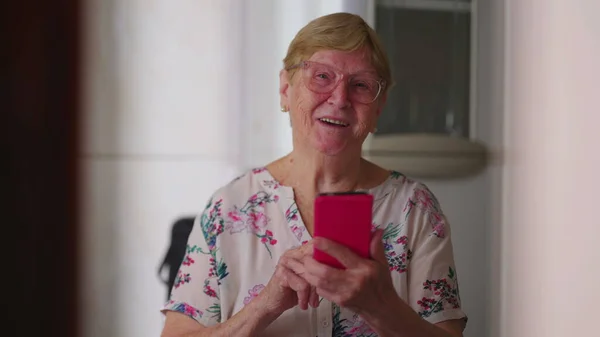 Szczęśliwa Seniorka Trzymająca Smartfon Patrząca Uśmiechniętą Kamerę Domowy Starość Styl — Zdjęcie stockowe