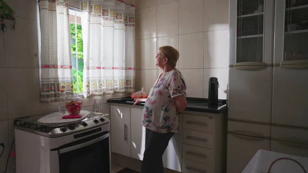 Contemplando Una Anciana Pie Junto Ventana Cocina Con Expresión Reflexiva — Foto de Stock