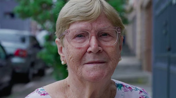 Close-up elderly woman face smiling while standing in city street looking at camera
