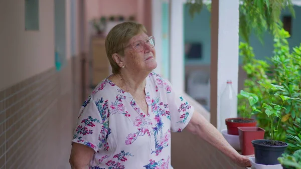 多愁善感的老妇人凝视着外面的家后院 80多岁的退休老年女性在家中做白日梦 — 图库照片