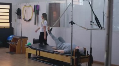 Rehabilitasyon sırasında Kıdemli Kadın Esneme Egzersizinde Yardımcı Pilates Eğitmeni