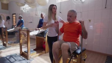 Pilates Makinesi 'nin kadın eğitmen tarafından çalıştırıldığı son sınıf egzersiziniz kutlu olsun. Yaşlılıkta vücut sağlığıyla ilgilenen yaşlı kişi rutin egzersiz yapar.