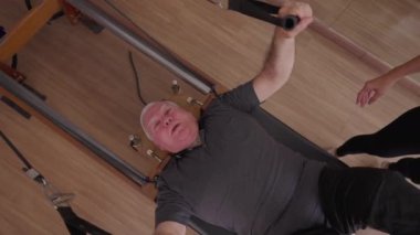 Yaşlılar için yorucu bir egzersiz olan Pilates Makinesi 'ni kullanarak vücudu güçlendiren kıdemli adam. Yukarıdan yakın çekim yüzü