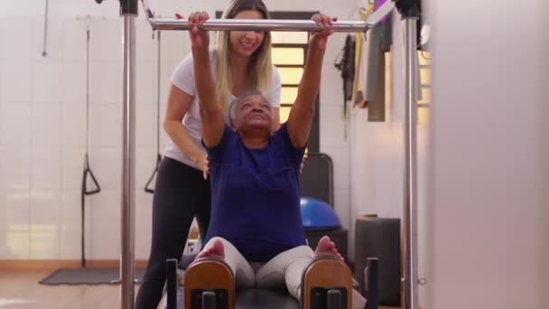 增强运动培训师的健身能力指导一位黑人老年妇女做普拉提运动 倡导健康的老年生活方式 — 图库视频影像