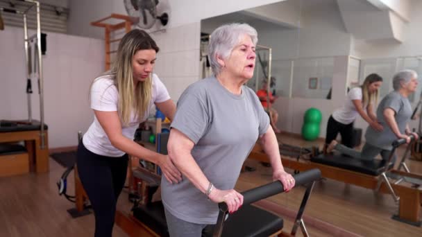 Pilates Instructeur Assisteren Senior Vrouw Stretching Oefening Tijdens Rehabilitatieve Sessie — Stockvideo
