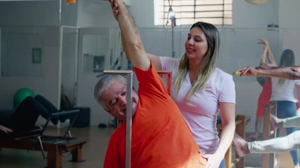 Trener Pilates Pomaga Starszemu Mężczyźnie Rozciągnąć Ciało Starość Trening Zdrowia — Wideo stockowe
