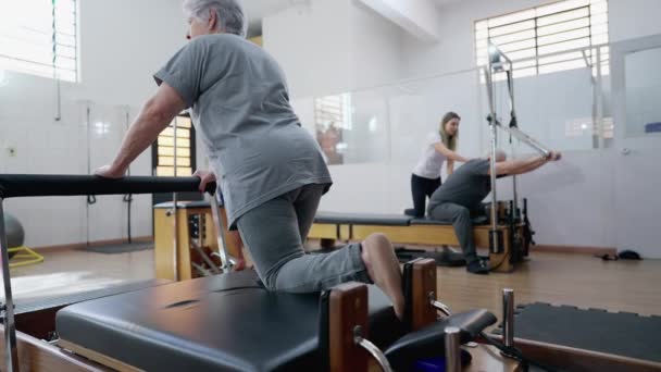 老年妇女的后背用普拉提机伸展身体 老年人的锻炼 — 图库视频影像