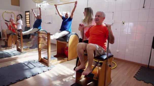 Pilates Teacher Coaching Senior Man Machine Group Physiotherapy Session Old — Stock Video